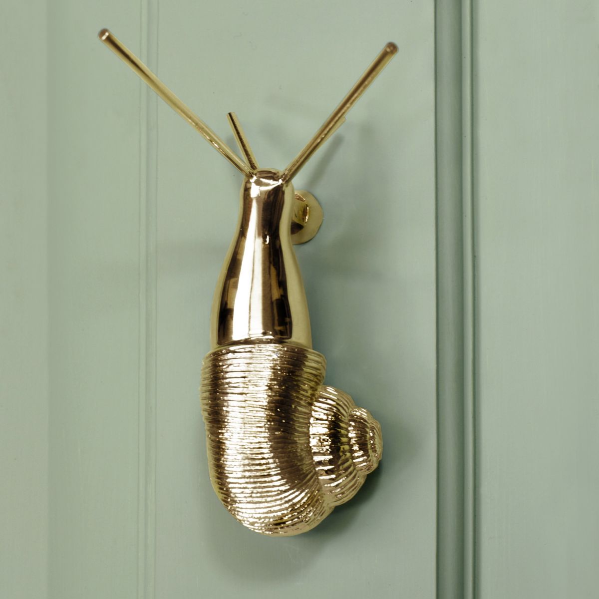 Polished brass Snail door knocker on pastel green door