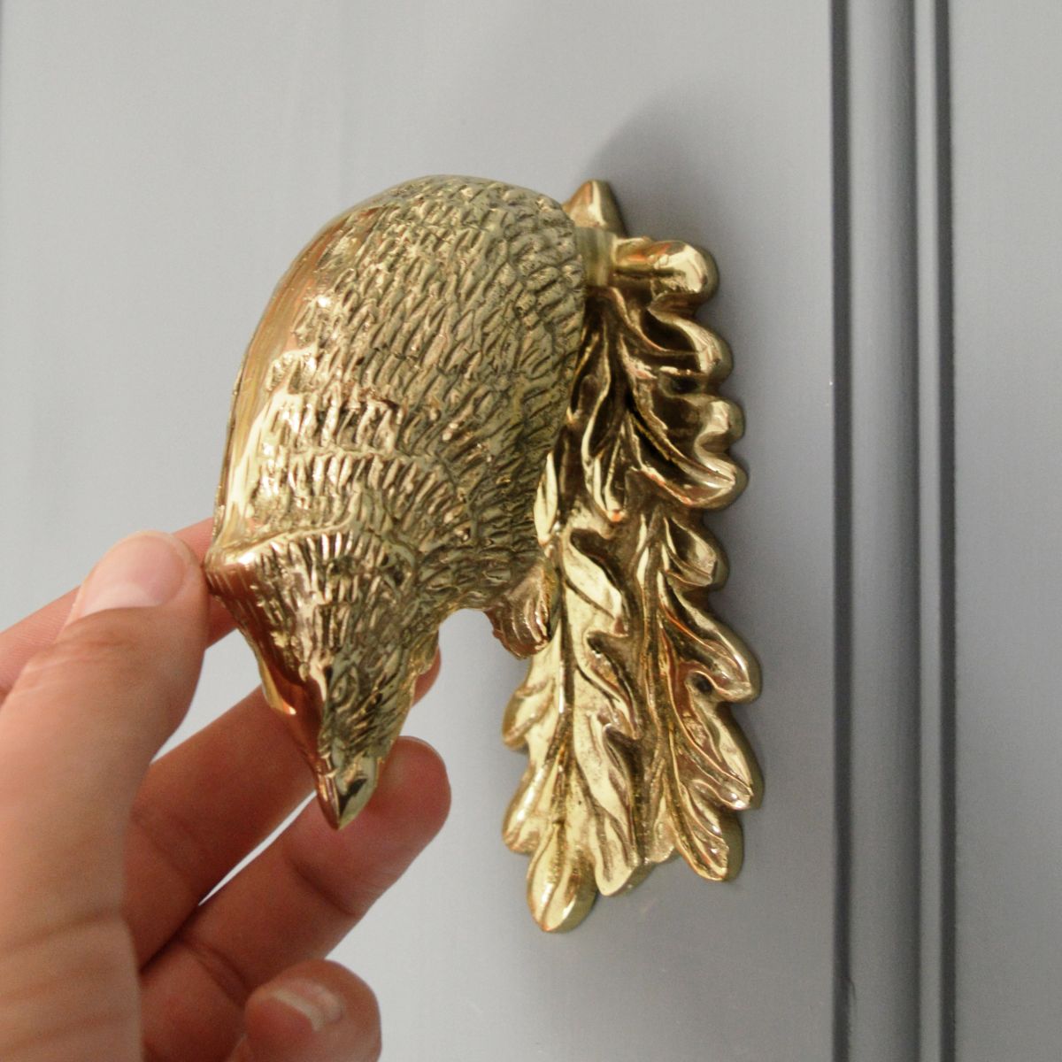Solid Brass Door Knocker on grey door, in use with hand