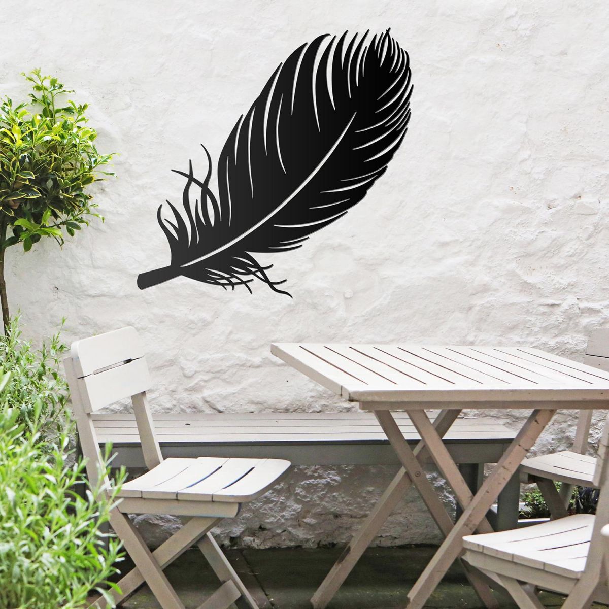Feather Wall Art in Use in the Garden Above a Wooden Table and Chair Set Feather Wall Art in Use in the Garden Above a Wooden Table and Chair Set