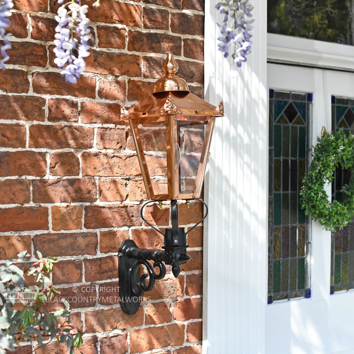 Genuine copper lantern on cast iron bracket mounted by front door Genuine copper lantern on cast iron bracket mounted by front door