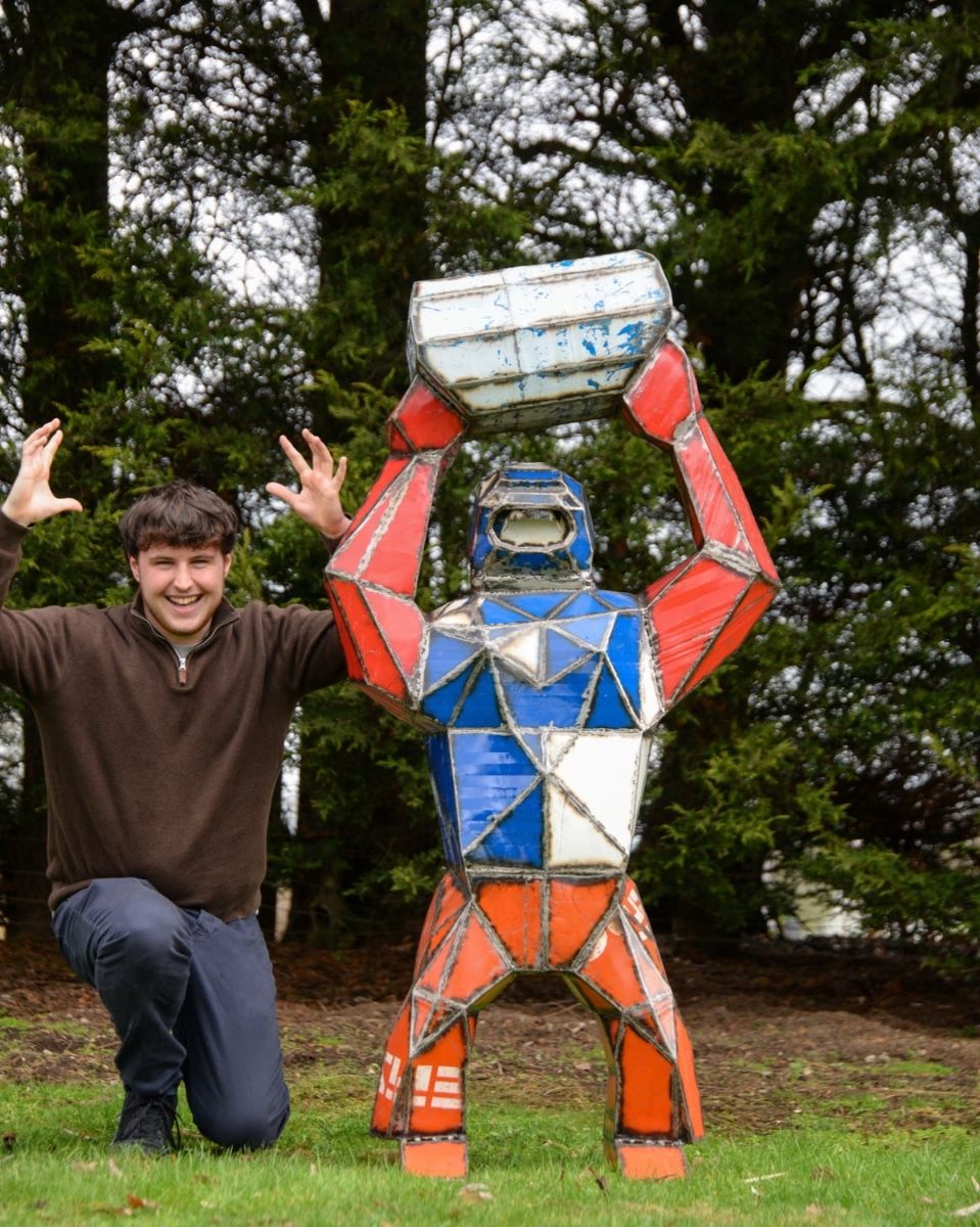 Gorilla Holding Barrel Upcycled Oil Drum Garden Sculpture with Man Crouched Next to Sculpture for Scale