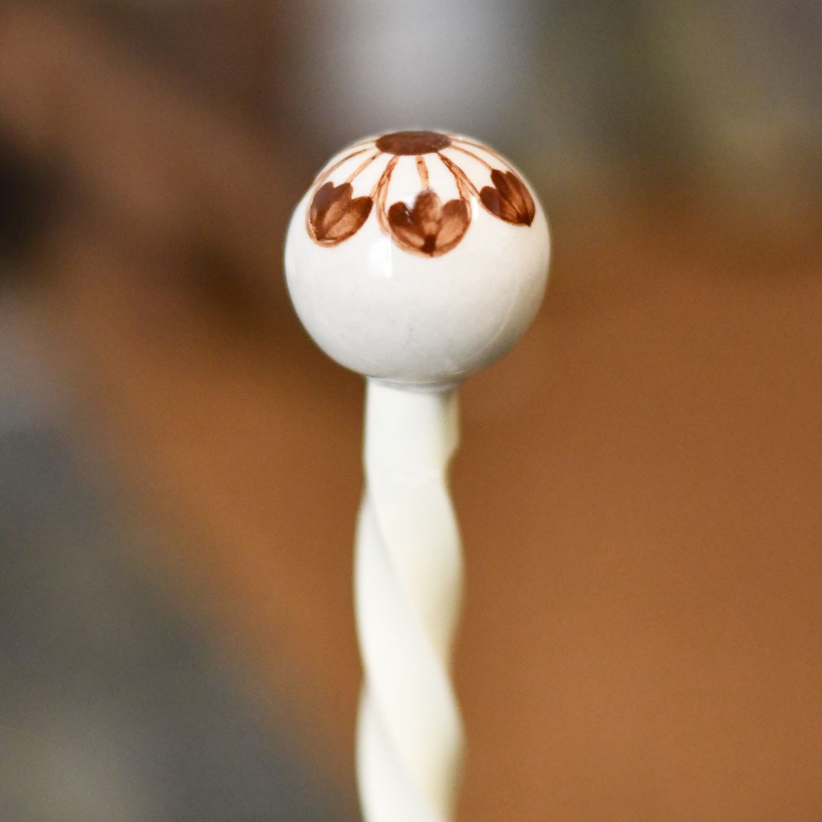 Close up image of ceramic cream & brown finial