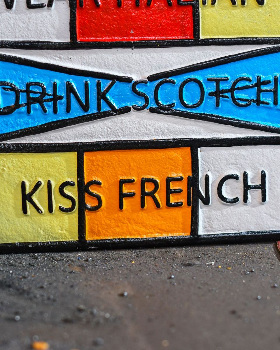 Close up of "Drive German, Wear Italian, Drink Scotch, Kiss French" Cast Iron Sign finish