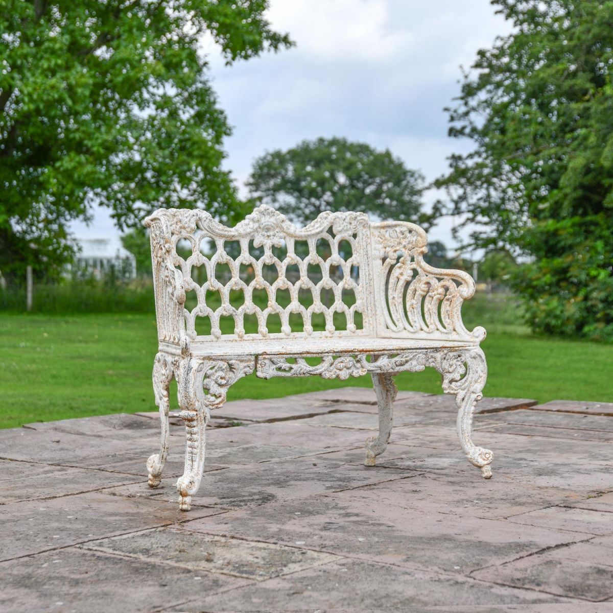 Antique Cream Ornate Cast Iron Garden Bench in Garden Setting Antique Cream Ornate Cast Iron Garden Bench in Garden Setting