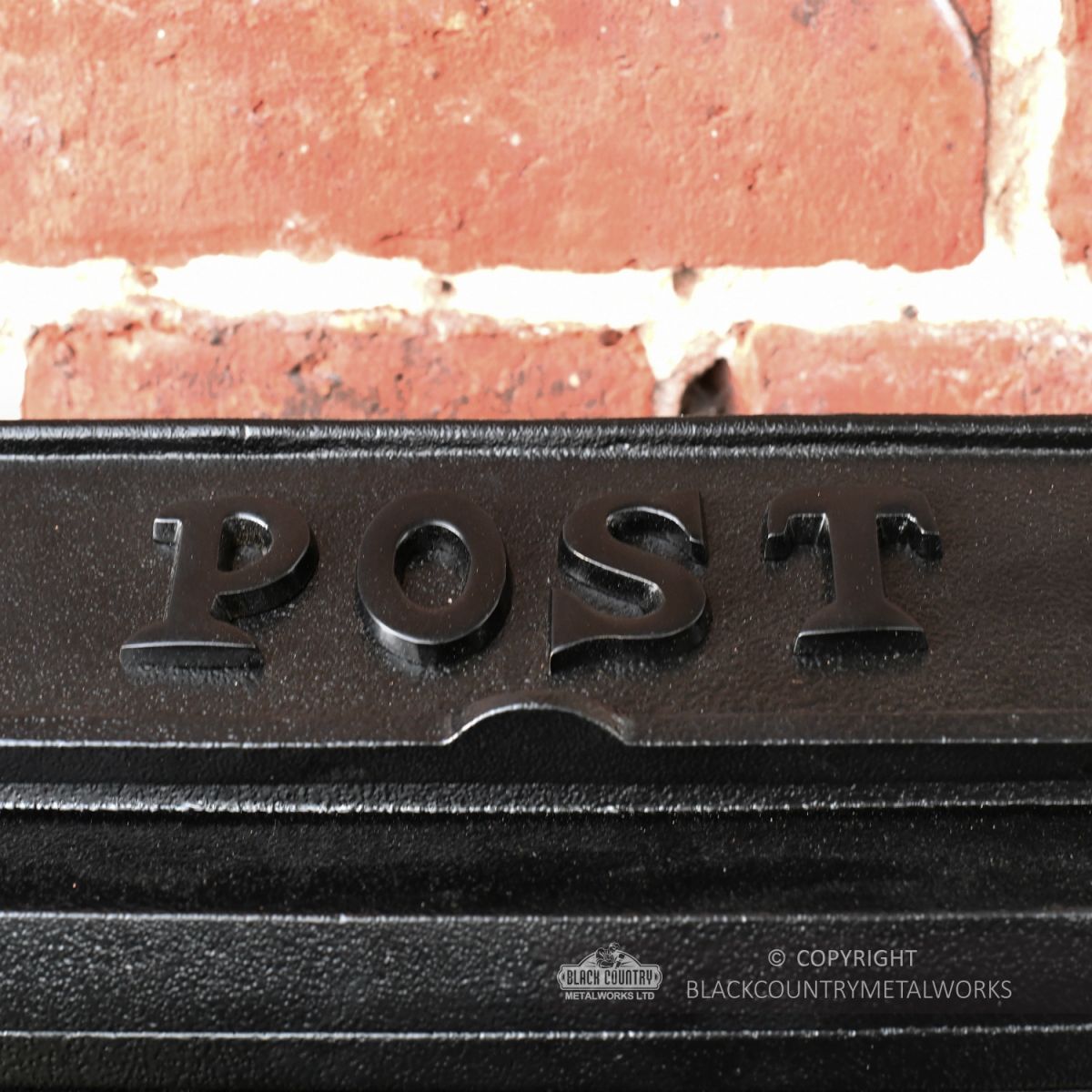 Close-Up of Text on Top of Simplistic Wall Mounted Post Box
