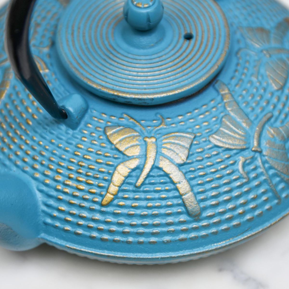 Close-Up of Golden Butterfly Design on Cast iron Teapot Close-Up of Golden Butterfly Design on Cast iron Teapot