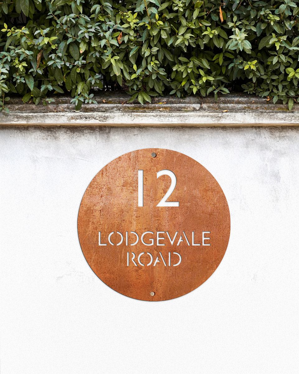 Modern Circular House Sign in Situ on a White Garden Wall