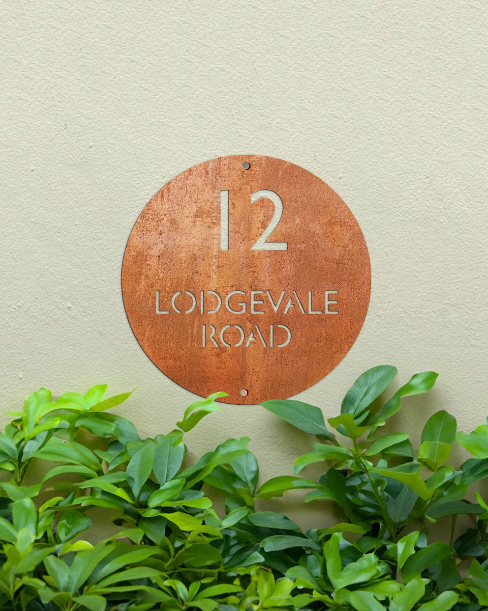 Modern Circular Corten Steel House Sign on a Green Painted Wall