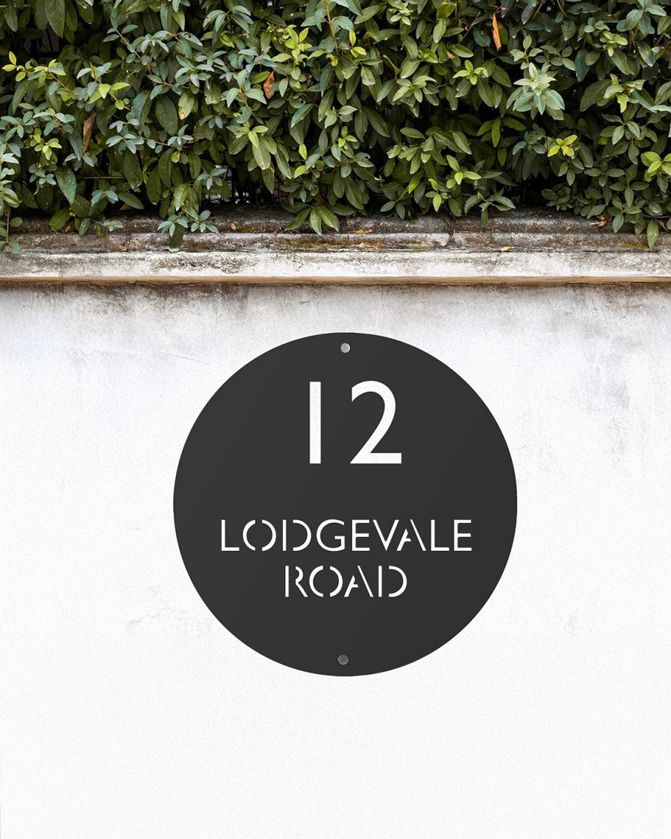 Modern Circular Steel House Sign on a White Garden Wall
