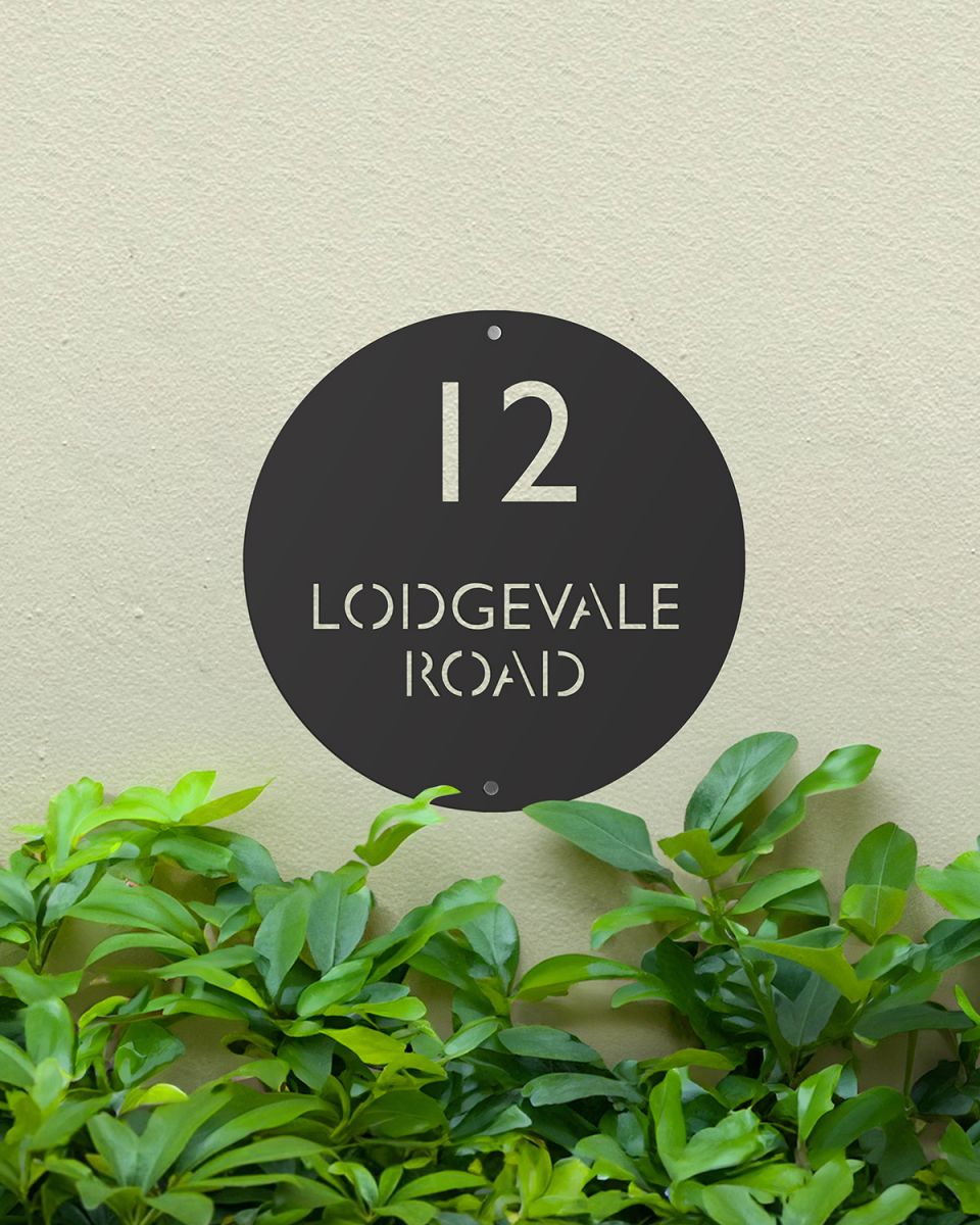 Modern Circular Steel House Sign Mounted onto a Painted House Wall