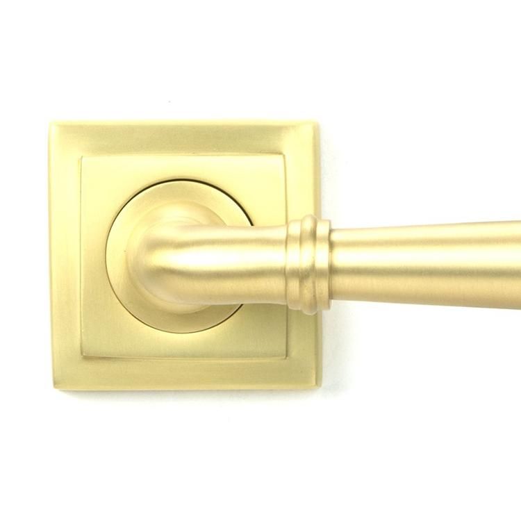 Close-Up of Modern Satin Brass "Neville" Unsprung Door Handle on Square Rose Set - 53mm