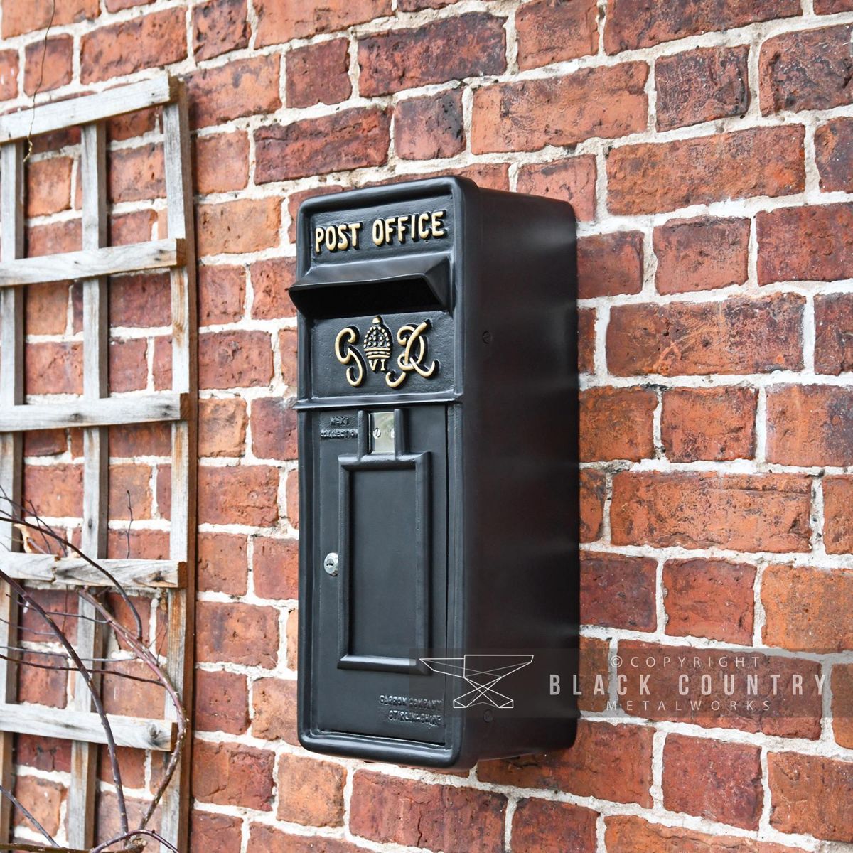 Black & Gold Slim King George Post Box in Situ on a Brick Wall