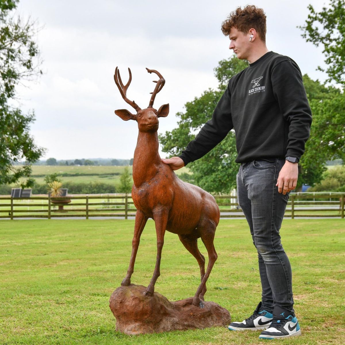 Male next to stag on rock sculpture for scale
