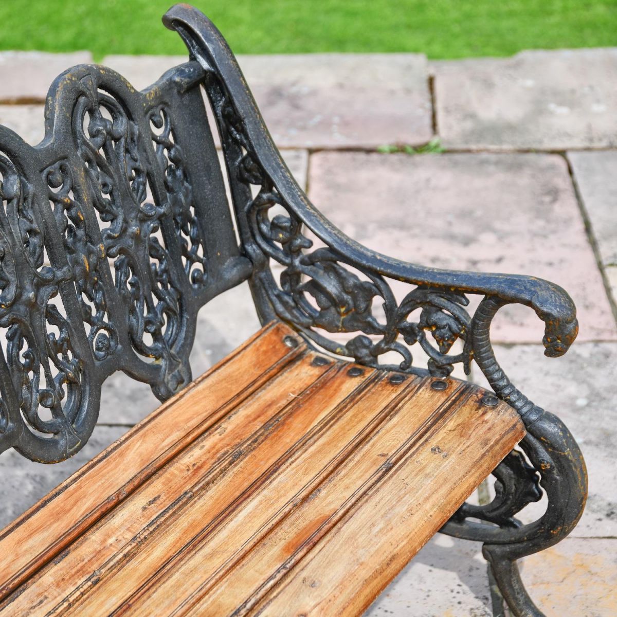 Close up of Aged Black Cast Iron Garden Bench with wooden slats