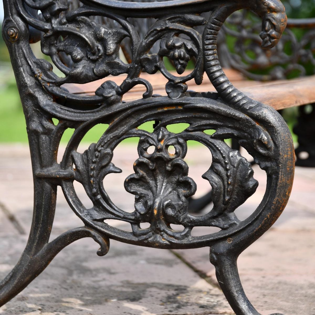 Close up of decorative embellishments on Aged Black Cast Iron Garden Bench