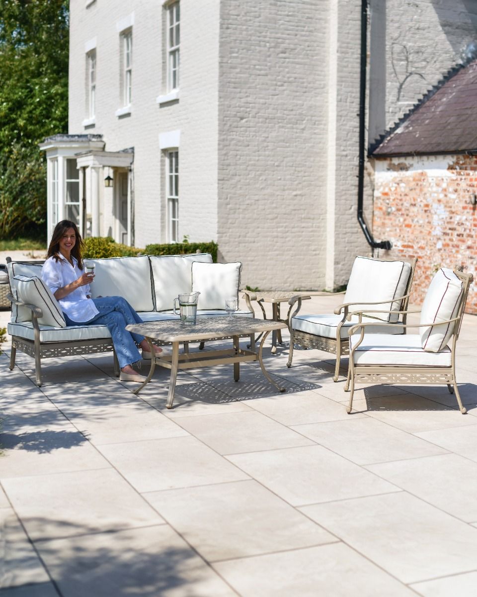 Wide shot of the Elmswood outdoor lunge set with a person sat on the sofa for scale