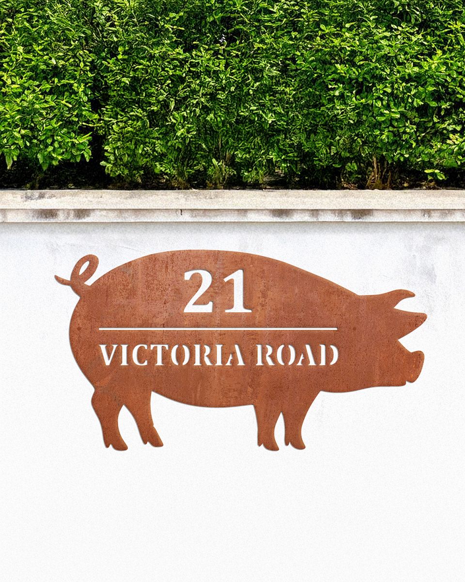 Pig Corten Steel House Name Sign on a White Garden Wall