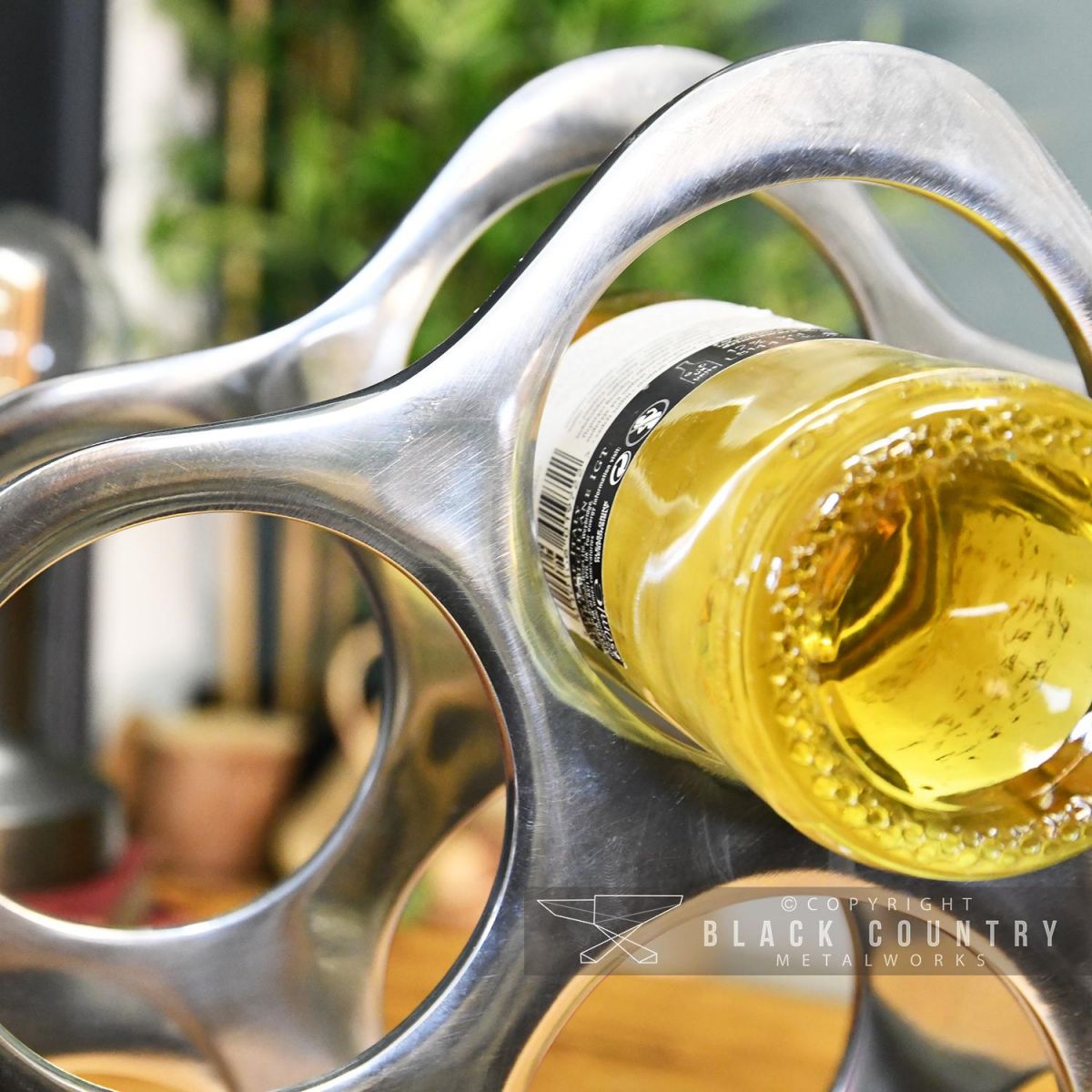 Close-up of a Wine Bottle Being Held Polished Nickel "Cloud" Wine Rack