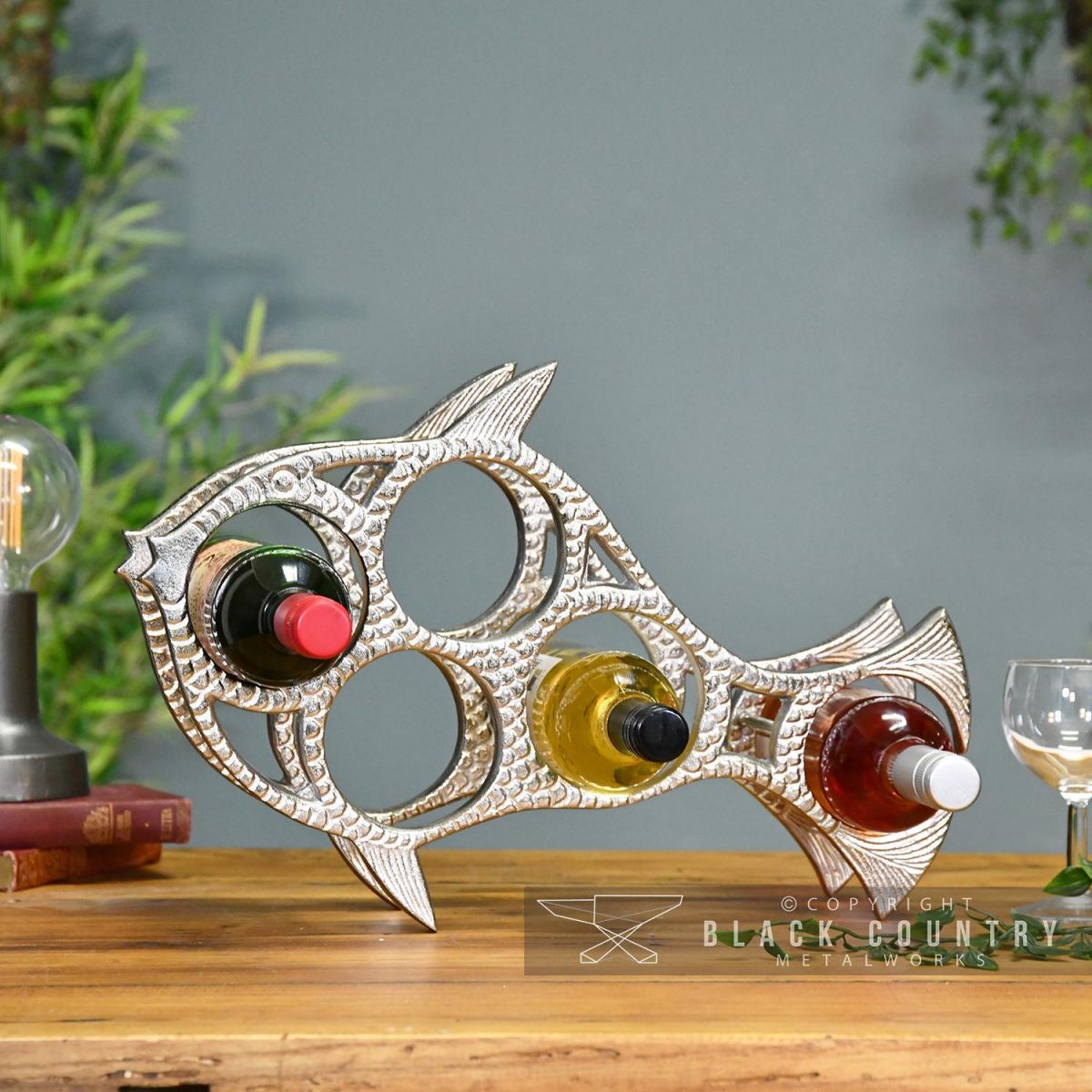 Polished Nickel "Fish" Wine Rack in Use Holding Wine Bottles Polished Nickel "Fish" Wine Rack in Use Holding Wine Bottles