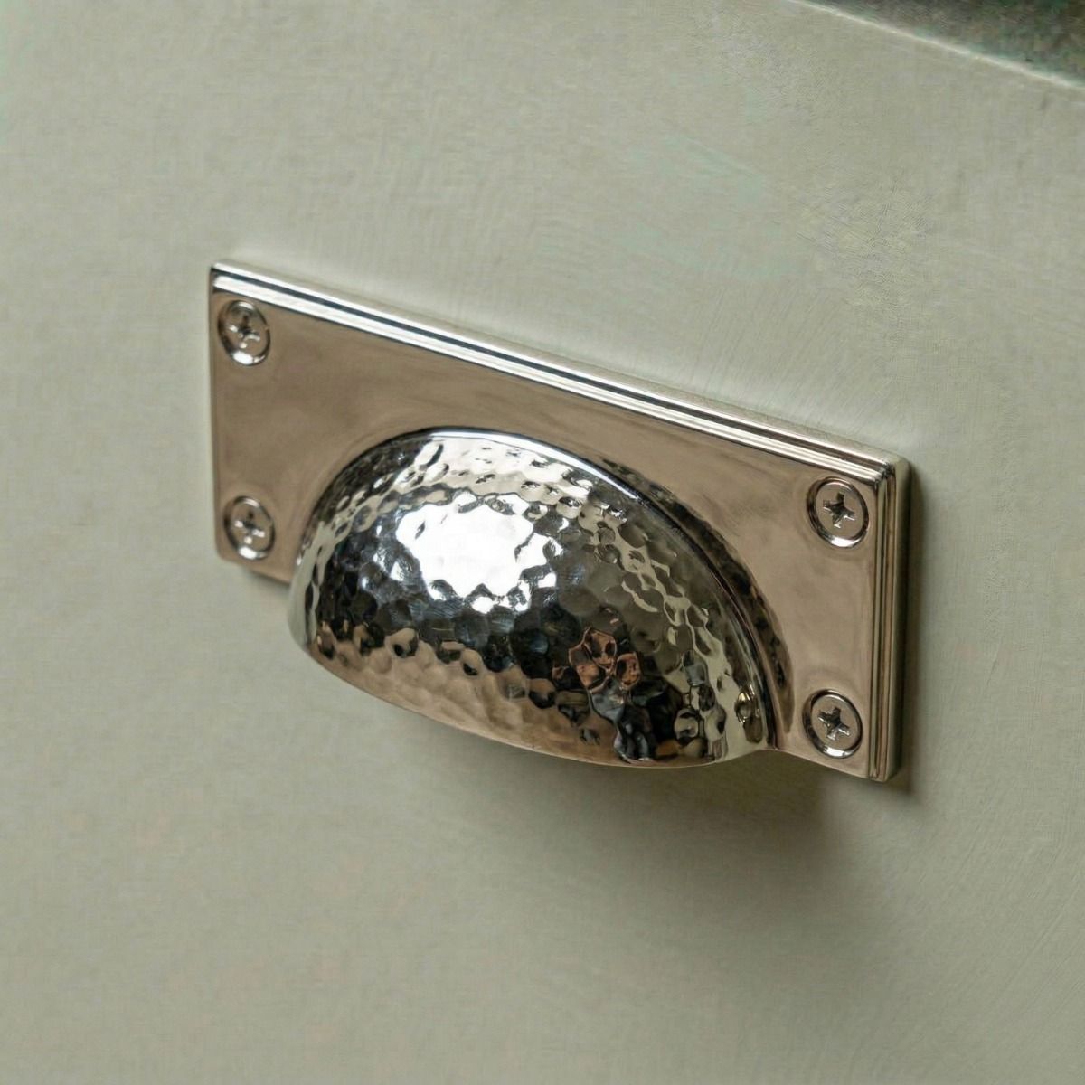 Digital Illustration of the Polished Nickel Rectangular Drawer Pull with Curved Hammered Handle Mounted on a Light Green Cupboard Door