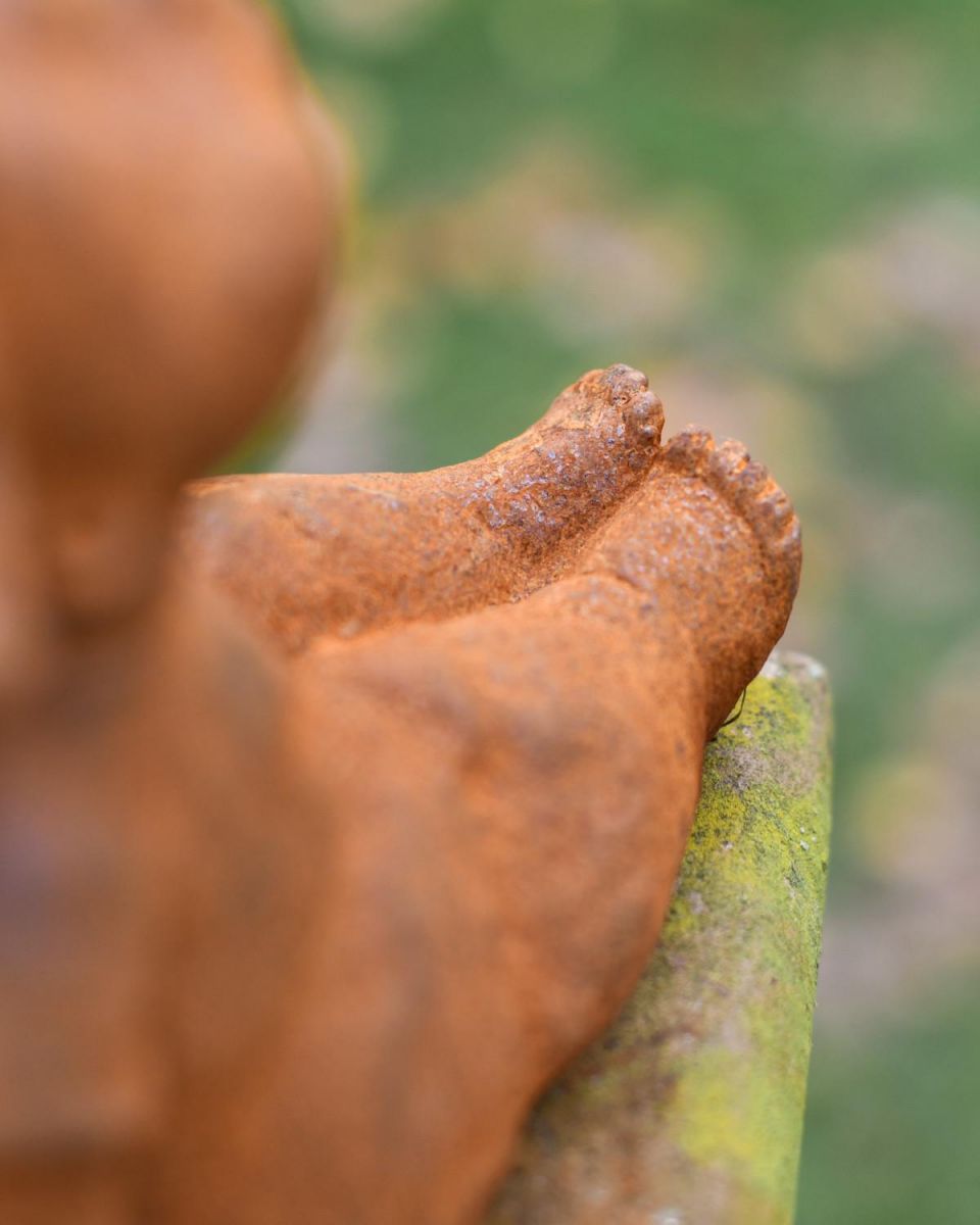 Close-Up of Feet on Rustic Cast Iron "Sunbathing Child" Garden Sculpture