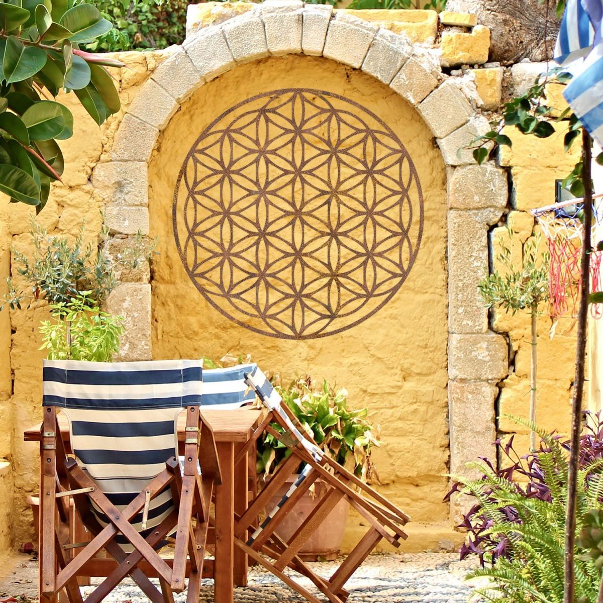 Geometry "Flower of Life" Steel Wall Art in a Display in the Garden on a Yellow Wall