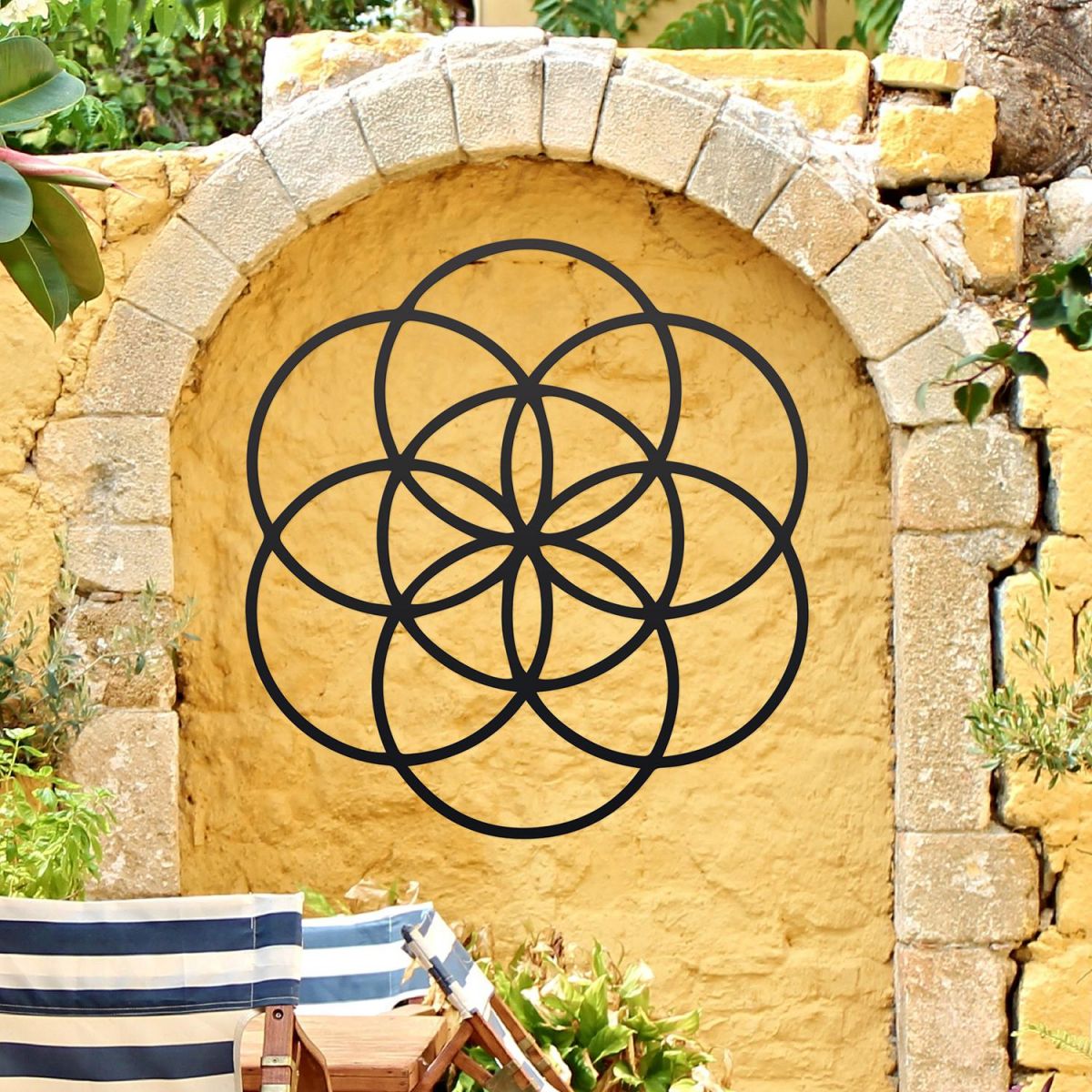 Black "Seed of Life" Steel Wall Art on a Yellow Garden Wall