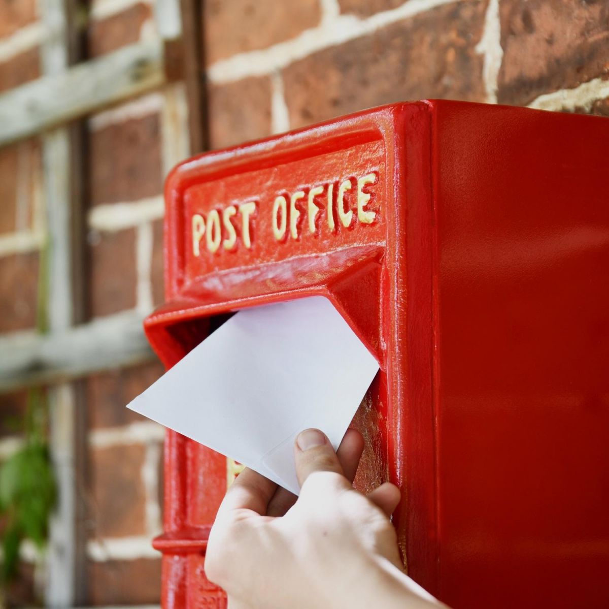 Letter Being Deposited into Red & Gold "Newland" Elizabeth Regina Post Box 