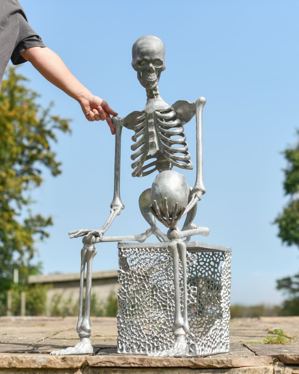 Scale image of skeleton holding skull outdoor statue