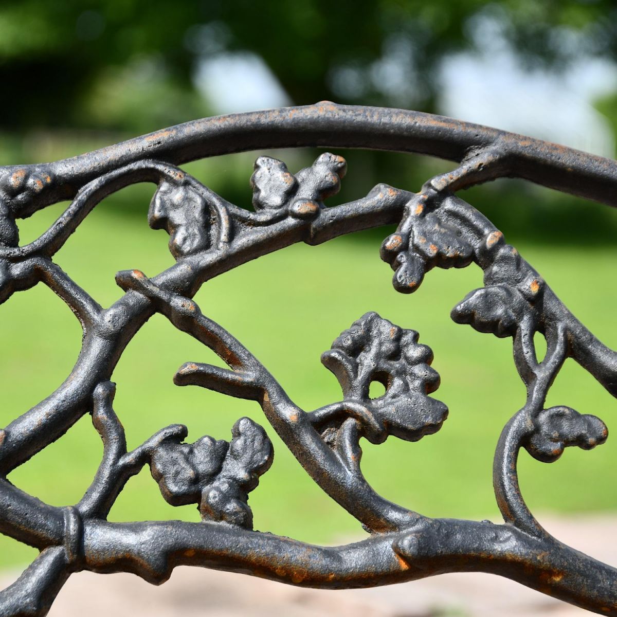 Close up of aged black cast iron branch detailing on garden bench