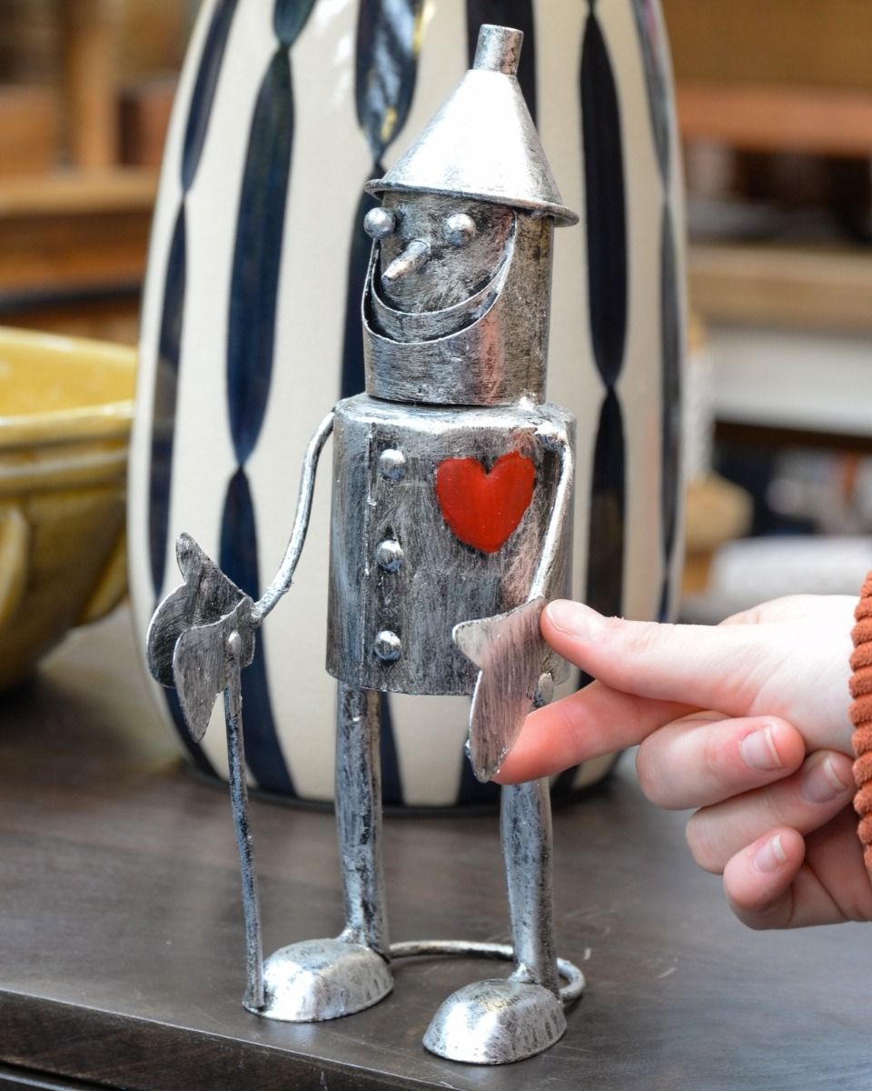 "Rusty" the Tin Man Standing Garden Ornament Stood on a Table next to a Vase with a Hand in Shot for Scale