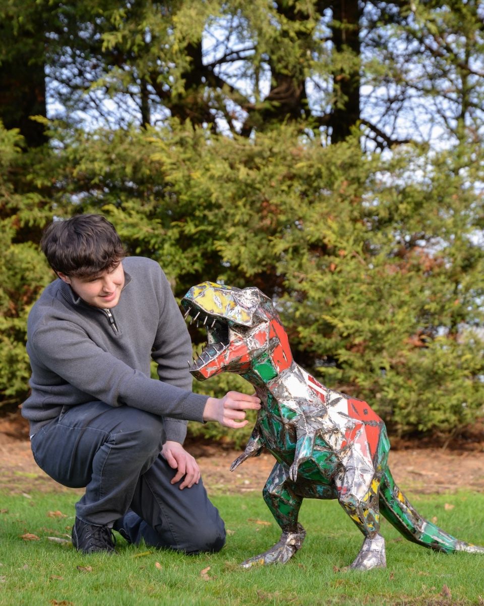 ‘Byte’ the T. Rex Upcycled Oil Drum Garden Sculpture with man crouching down next to sculpture
