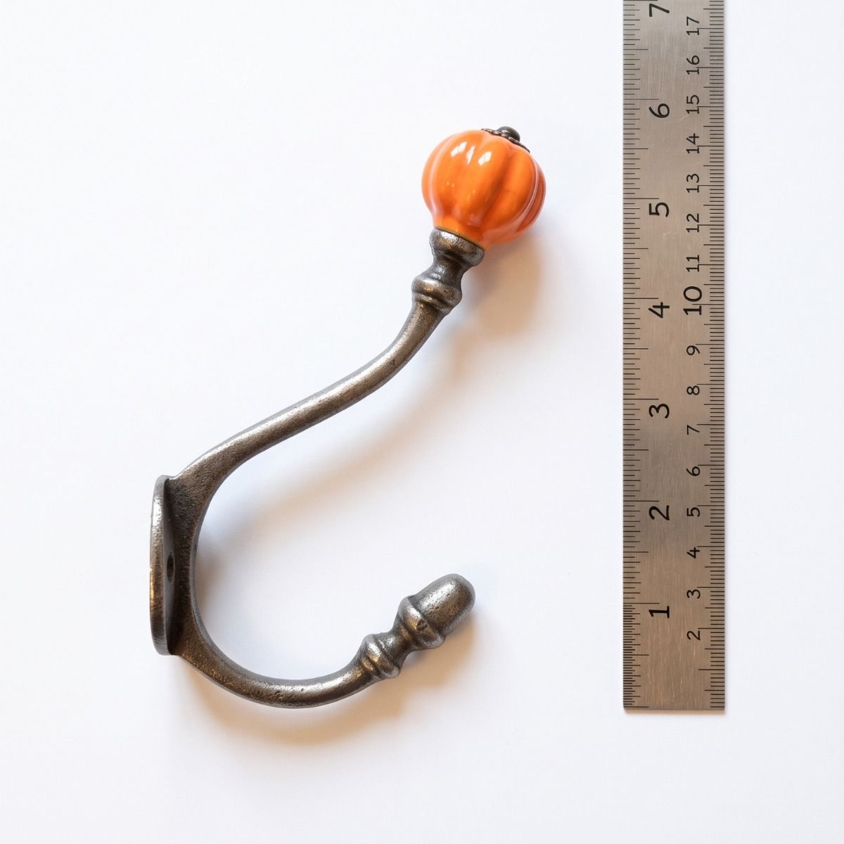 The 125mm Ironmonger Acorn Orange Ceramic Coat Hook On a White Background  next to a Ruler for Scale - Digital Illustration
