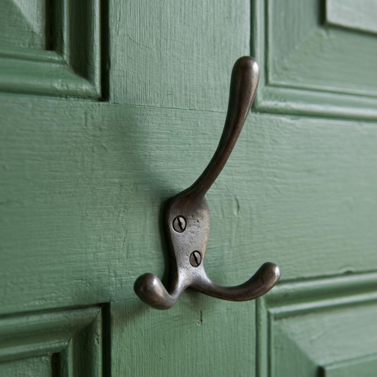The Blacksmith Vintage Cast Iron Three-Prong Hall Hook - 100mm Mounted on a Green Door - Digital Illustration