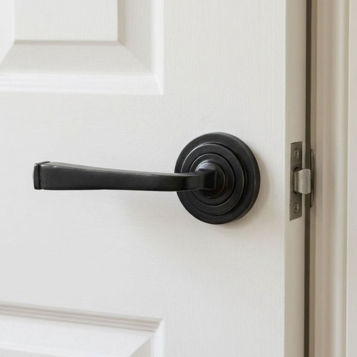 The Grayson Manor Midnight Black Unsprung Lever Door Handle on Art Deco Rose Shown Mounted on a Bright White Door - Digital Illustration