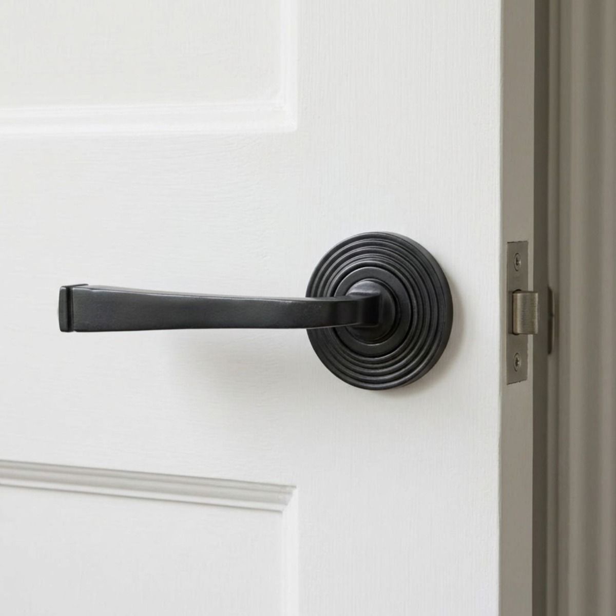 The Grayson Manor Midnight Black Unsprung Lever Door Handle on Beehive Rose On a Bright White Door Shown Close up - Digital Illustration