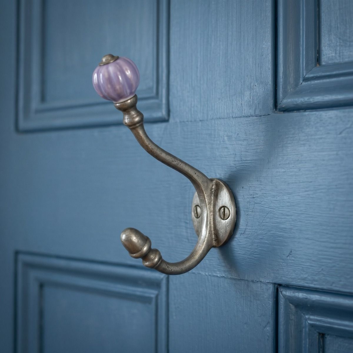 The Ironmonger Acorn Purple Ceramic Coat Hook - 125mm Shown up Close on the Back of a Blue Door - Digital Illustration