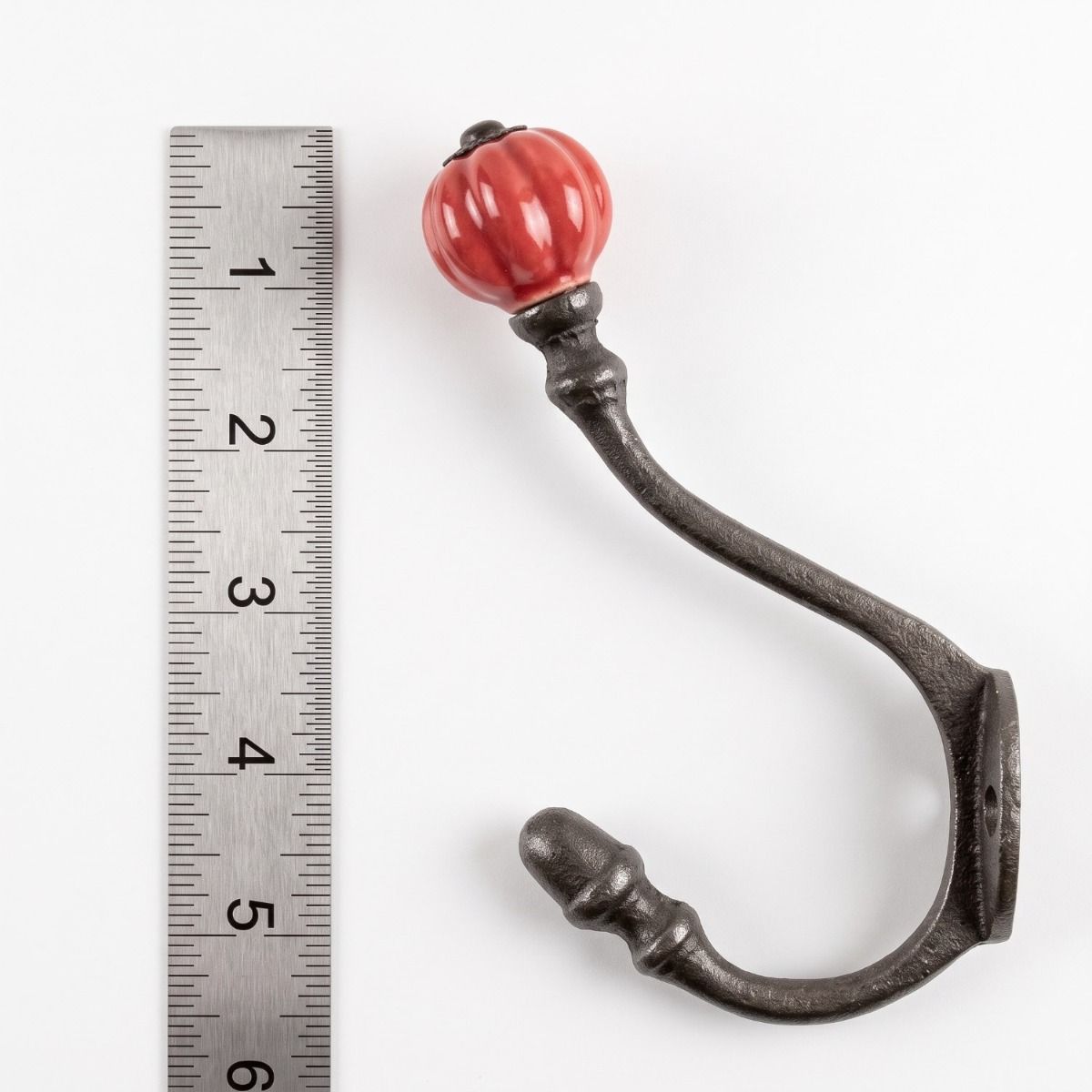 The Ironmonger Acorn Rose Red Ceramic Coat Hook - 125mm on a White Background next to a Steel Ruler for Scale - Digital Illustration