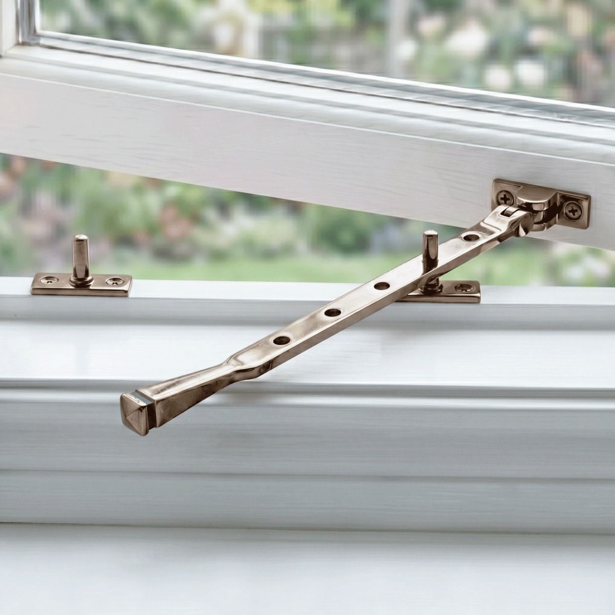 The 12" Polished Bronze Window Stay Mounted on an Open White Window in a Contemporary Home - Digital Illustration