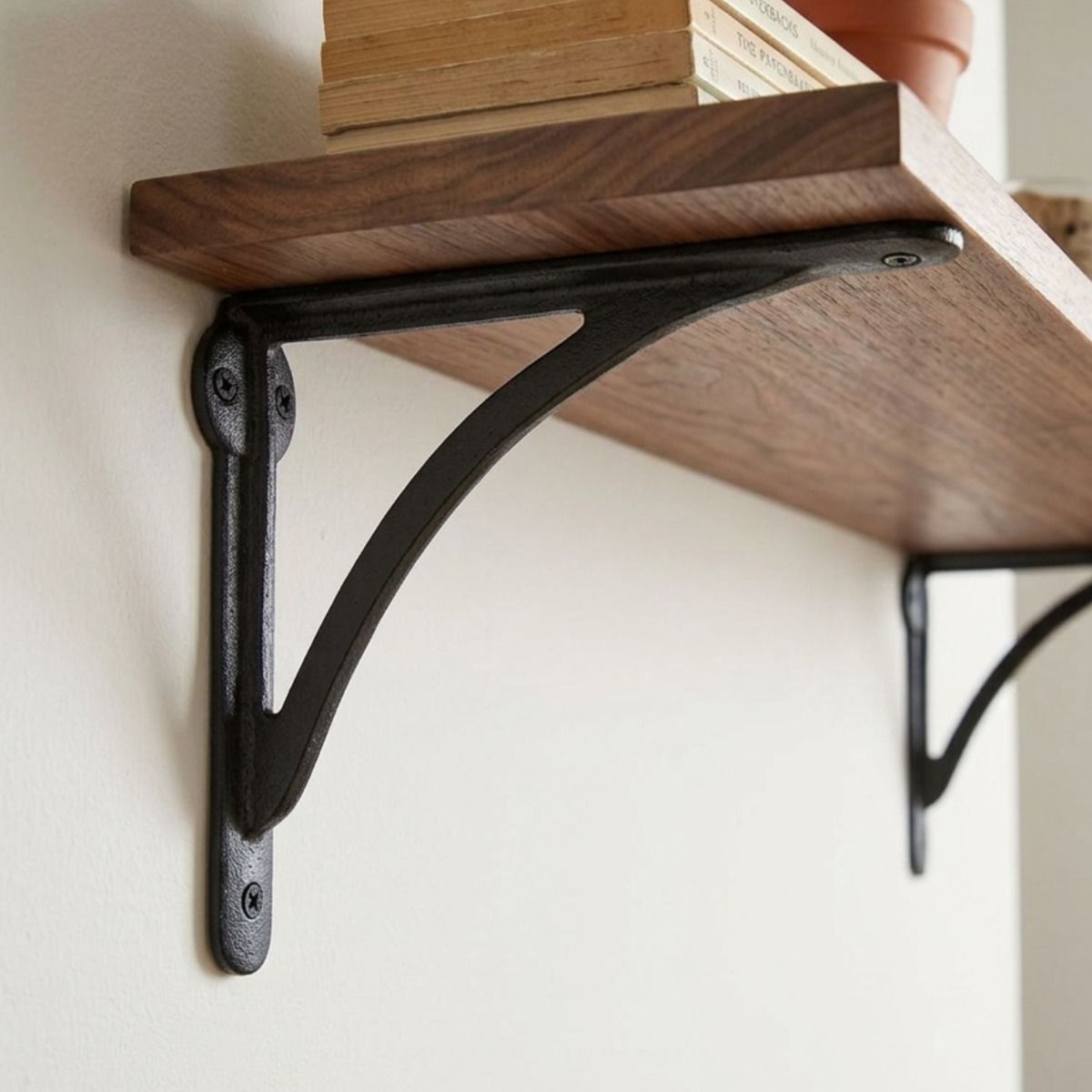 The 18 x 25cm "Bowfell" Curved Black Iron Shelf Bracket on a Cream Coloured Wall in a Modern Interior - Digital Illustration