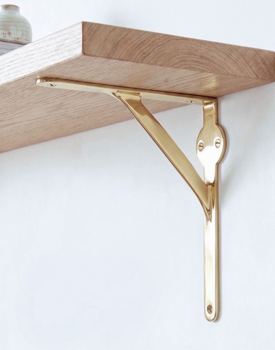 The 21 x 21cm Polished Brass Stylish Gallows Bracket Mounted on a Clean White Living Room Wall as A Wall Hanger - Digital Illustration 