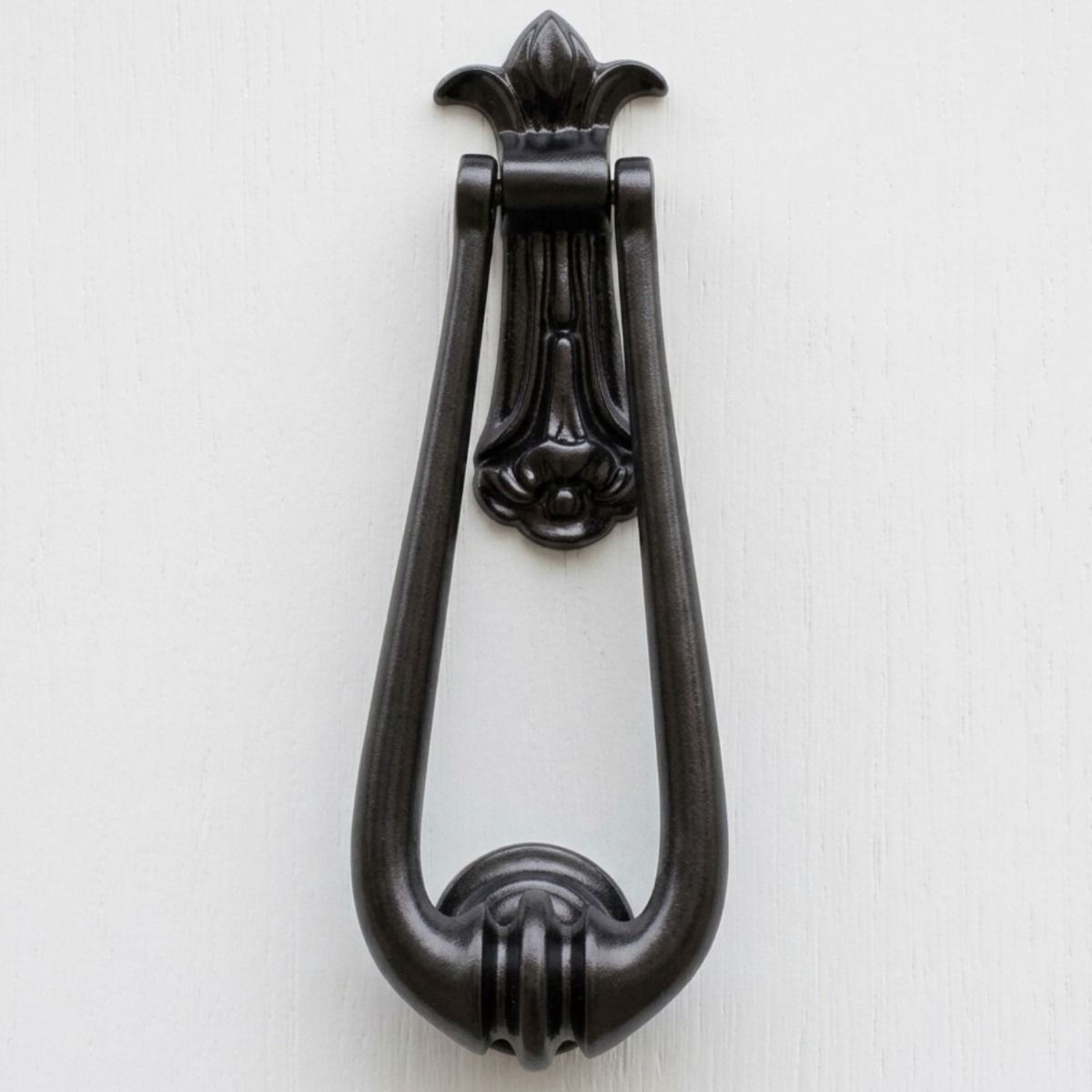 The "Addison Loop" Door Knocker in a Black Finish Shown on a White Door close up - Digital Illustration