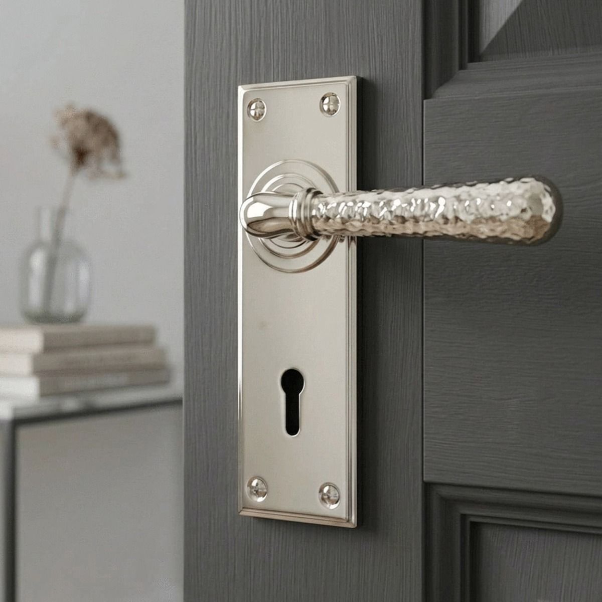 The "Amsden House" Hammered Polished Nickel Lever Lock Door Handle on a Light Grey Door in a Cream Coloured Home Interior - Digital Illustration
