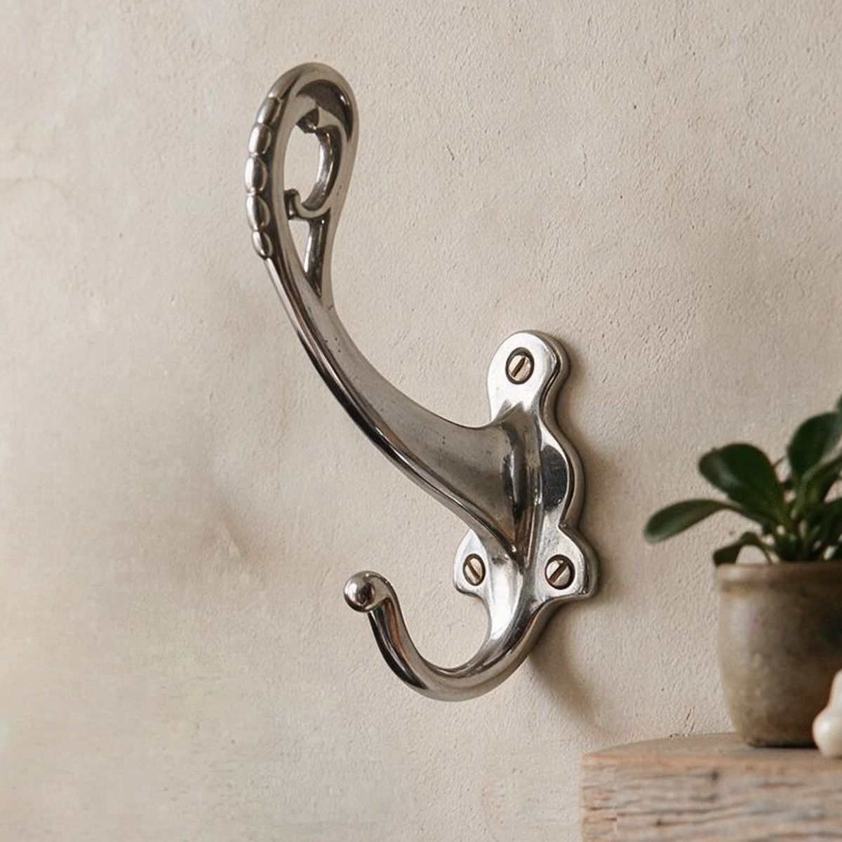 The "Becksly Park" Loop Hook with Shaped Backplate in Bright Chrome on a Textured Wall - Digital Illustration 