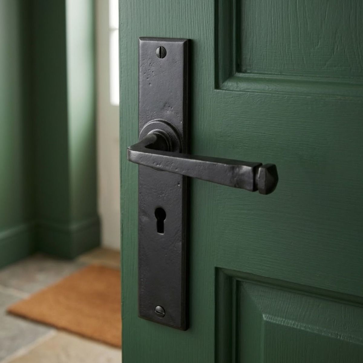 The "Buckthorn" Black Large Lever Lock Set Mounted on a Green Door in a Home Entrance - Digital Illustration