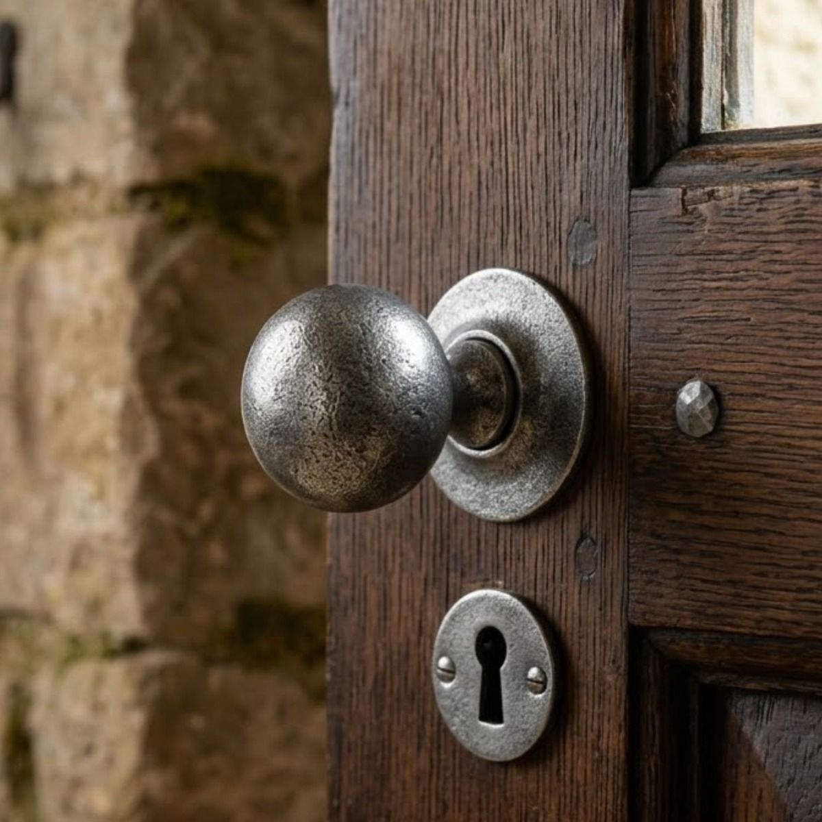 The "Clarendon" Pewter Ball Mortice or Rim Knob Set with Escutcheons on a Traditional Wooden Door next to a Matching Keyhole - Digital Illustration 