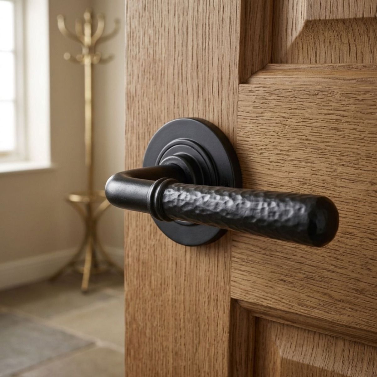 The "Franbury" Black Hammered Lever Door Handle on Rose on a Wooden Door in a Home Entrance with Coat Stand - Digital Illustration