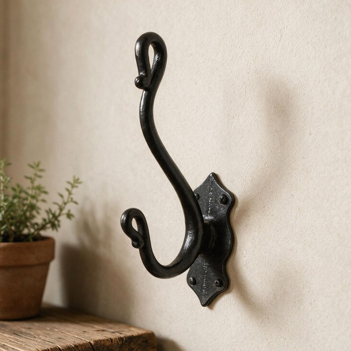 The "Halkdale" Iron Coat Hook on a Magnolia Coloured wall next to a Timber Shelf - Digital Illustration