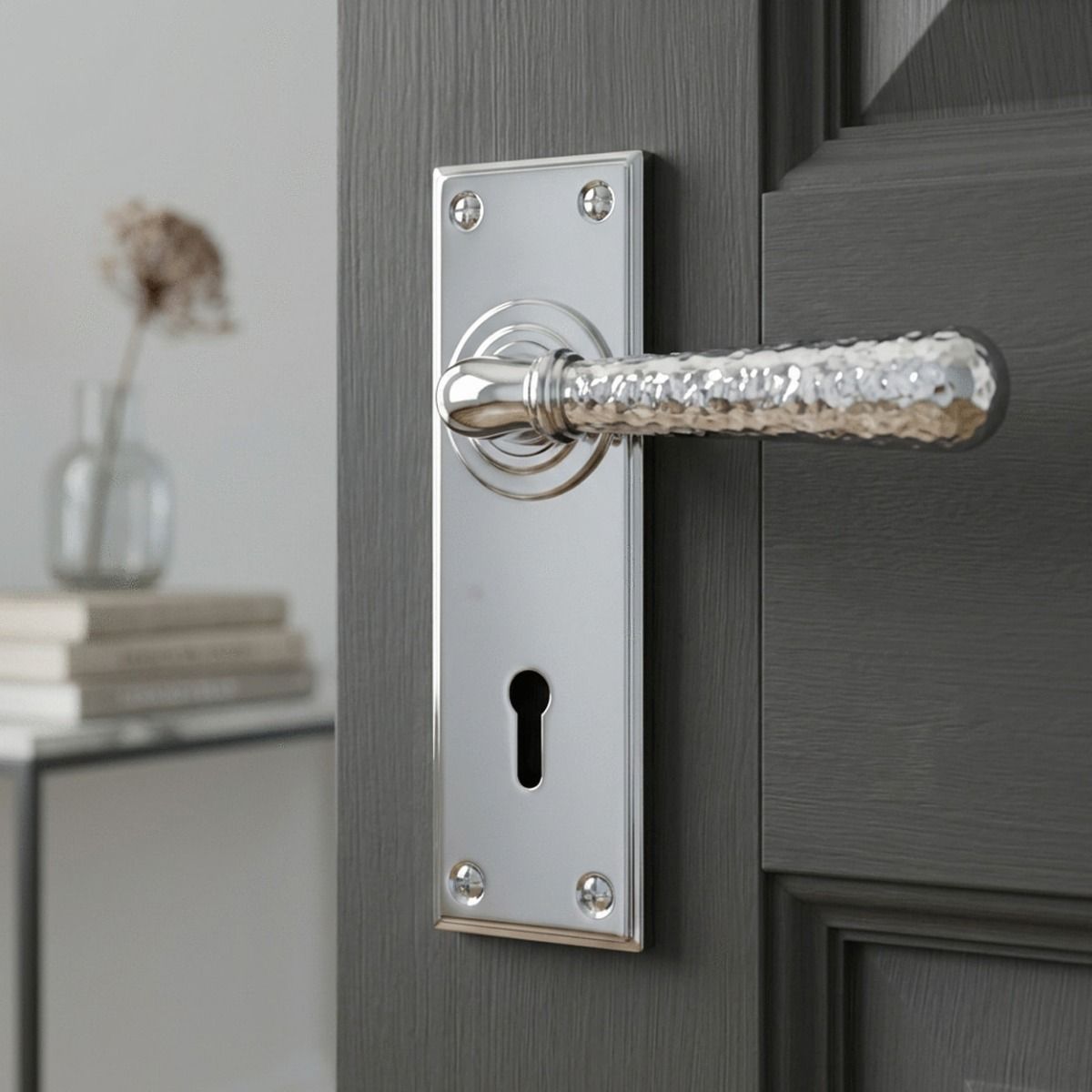 The "Harriot House" Hammered Bright Chrome Lever Lock Door Handle on a Charcoal Grey Door in a Cosy Home Interior - Digital Illustration