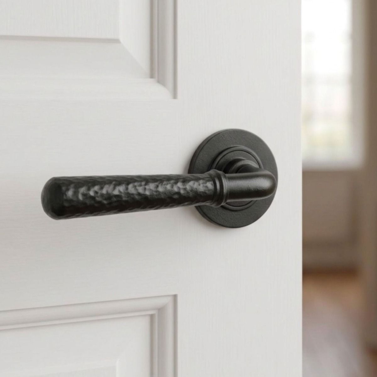 The "Hunter Lodge" Midnight Black Hammered Unsprung Lever Door Handle on Rose on a White Door in a Modern Living Room - Digital Illustration